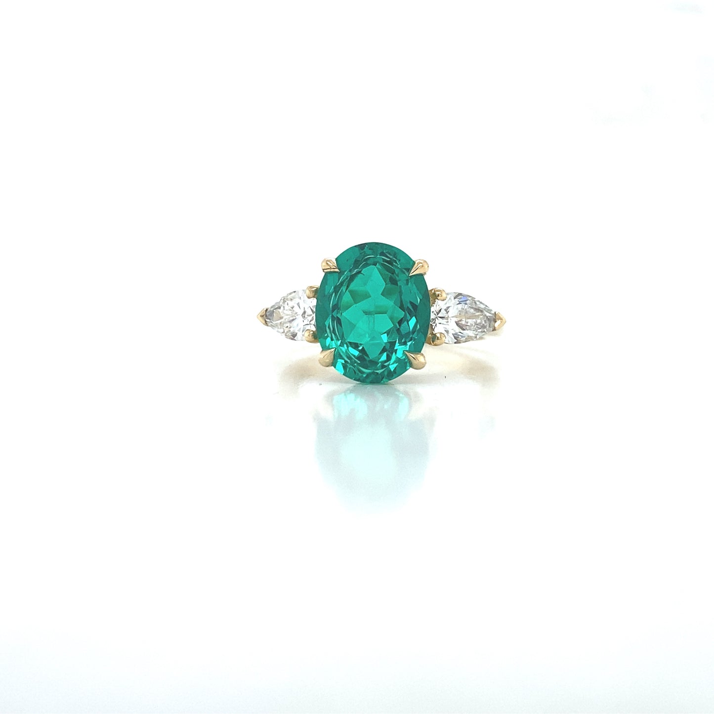 Oval emerald with pear shaped diamond side stones in 18ct yellow gold